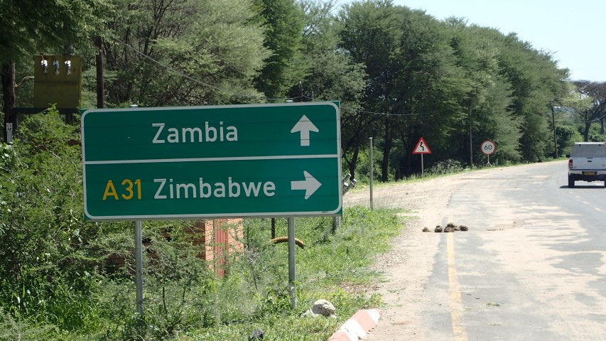 The borders of Namibia, Zambia, Zimbabwe and Botswana all meet near Kasane. Note Elephant droppings on the road next to sign.
